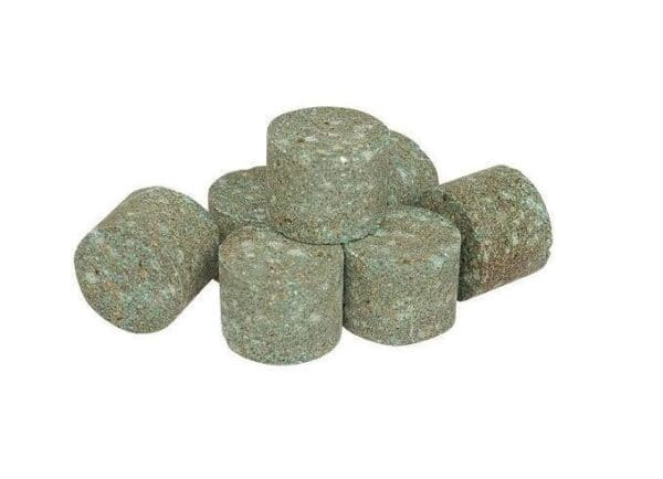 A pile of green fertilizer tablets sitting on top of each other.