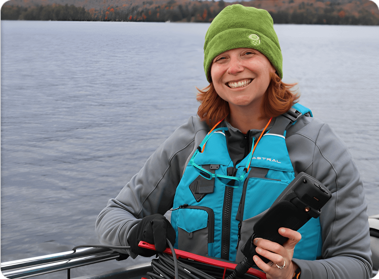 Woman smiling on a boat holding equipment.